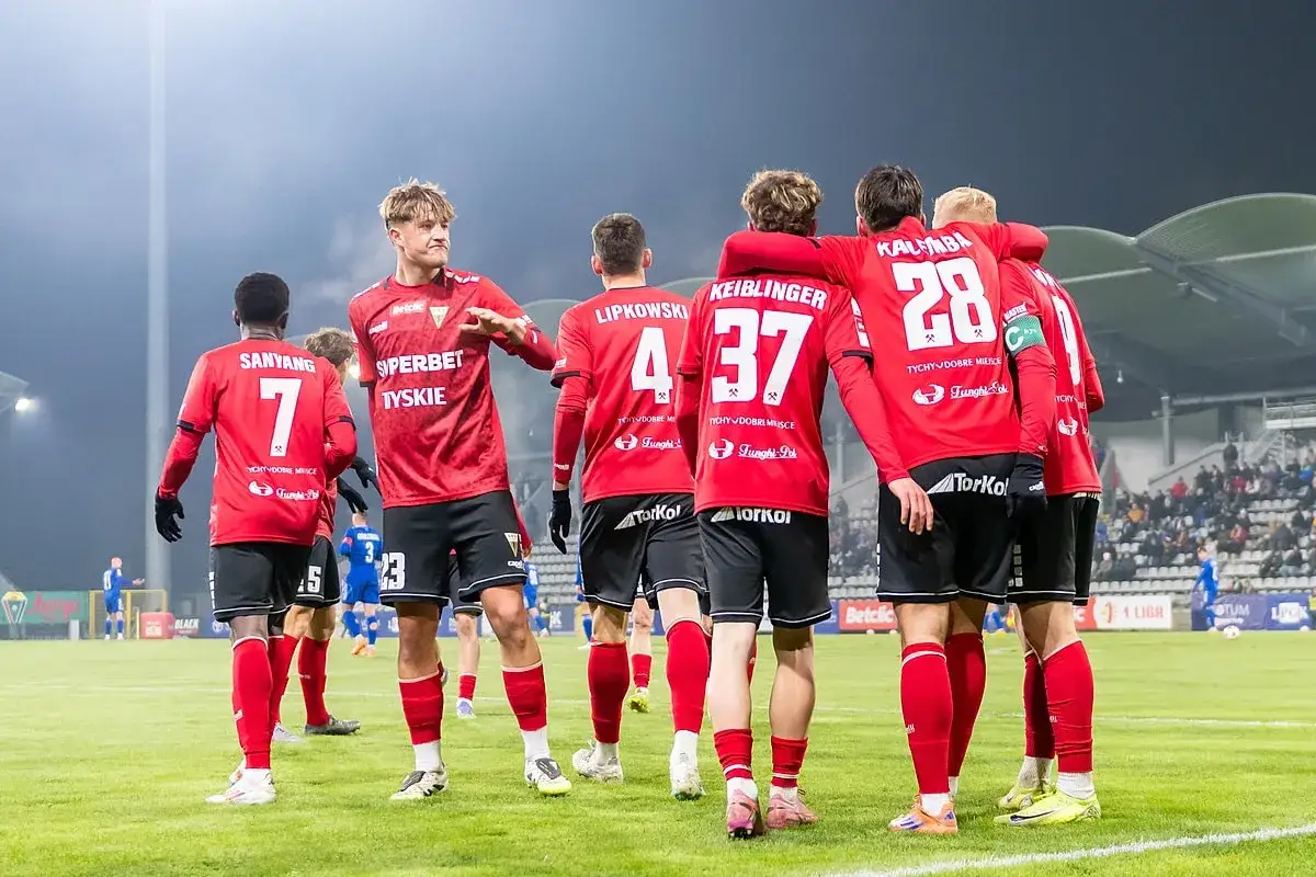 Piłkarze GKS Tychy w czerwonych strojach świętują na boisku. Wszyscy czekają na kolejne gks tychy transfery.