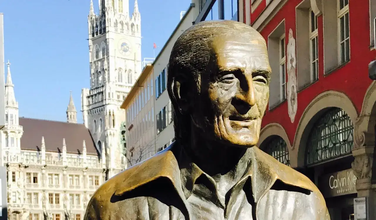 Bronzestatue von Sigi Sommer in München, mit dem Neuen Rathaus im Hintergrund.