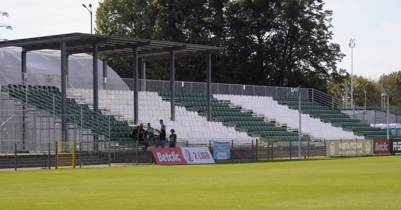 Puste trybuny małych stadionów piłkarskich, z zielonymi i białymi siedzeniami, czekają na kibiców.
