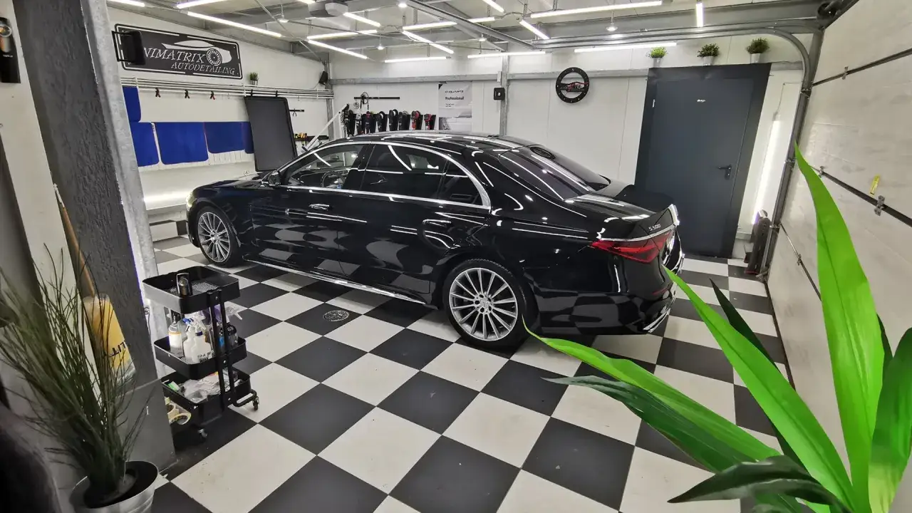Lśniący czarny Mercedes czeka na profesjonalny auto detailing w nowoczesnym garażu.