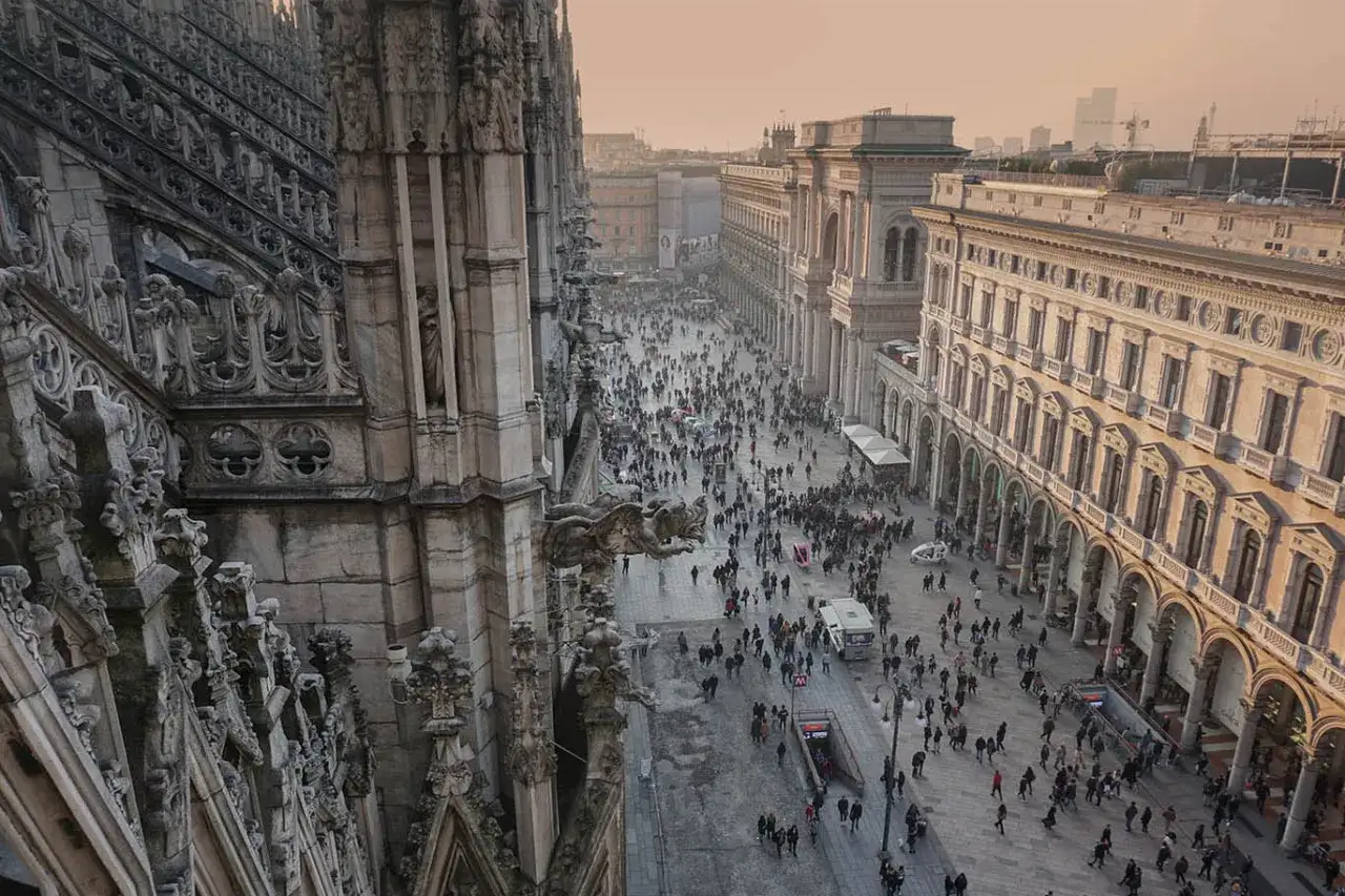 Dettaglio architettonico del Duomo di Milano con una piazza affollata di turisti e passanti.