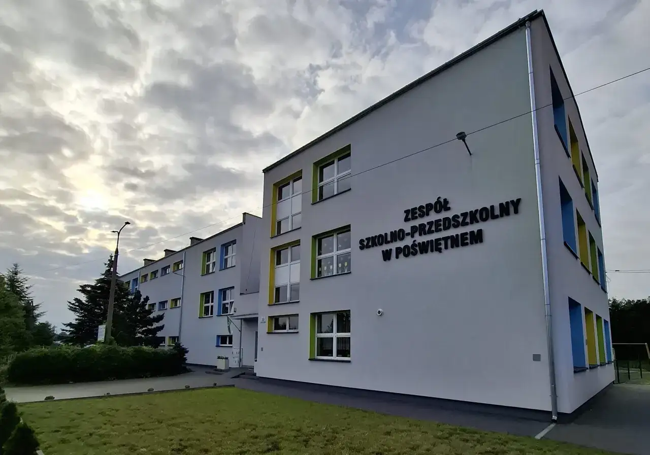 Nowoczesny budynek Zespołu Szkolno-Przedszkolnego w Poświętnem z kolorowymi ramami okien.