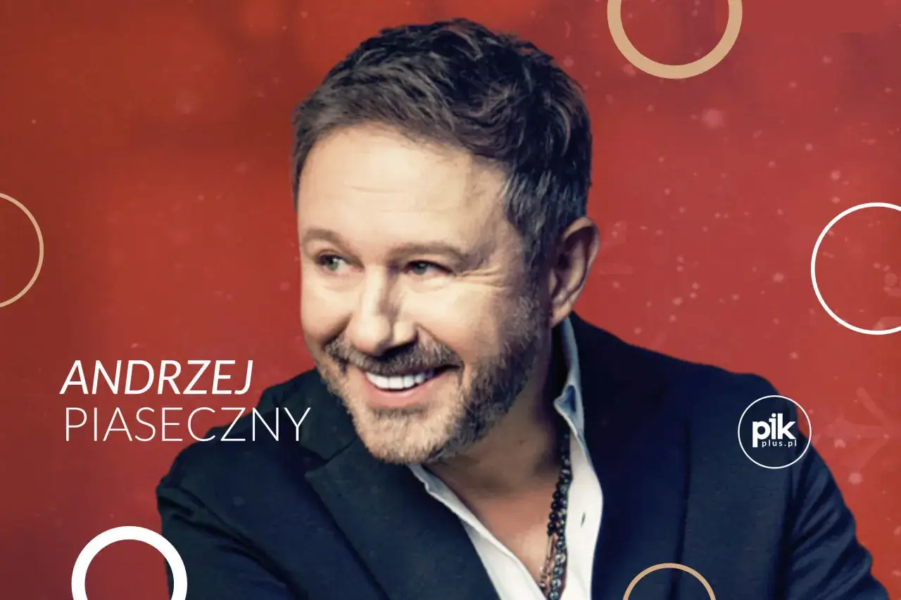 Uśmiechnięty Andrzej Piaseczny w czarnym garniturze. Choć na zdjęciu nie ma jego żony, jego promienny uśmiech sugeruje szczęście.