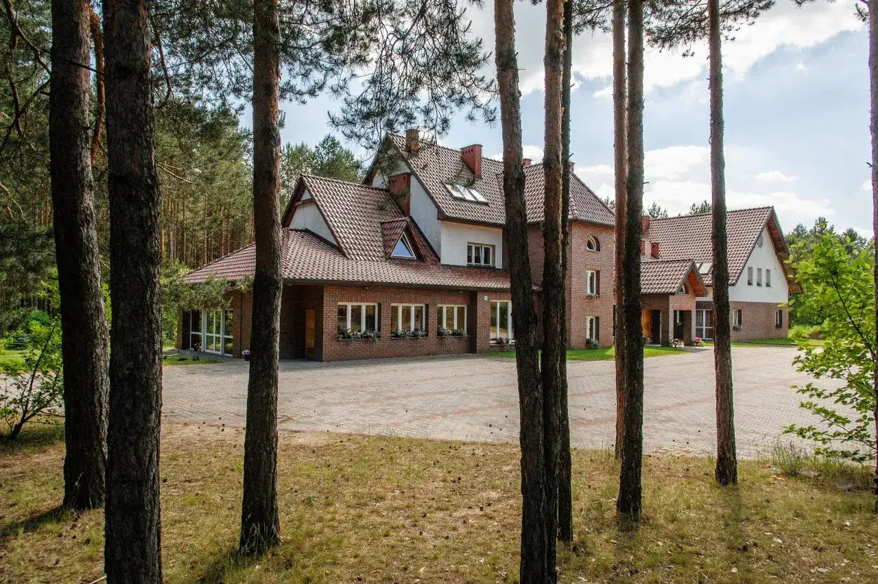 Ośrodki wypoczynkowe w górach dla rodzin z dziećmi, otoczone lasem sosnowym, z ceglanymi budynkami i dużym placem.