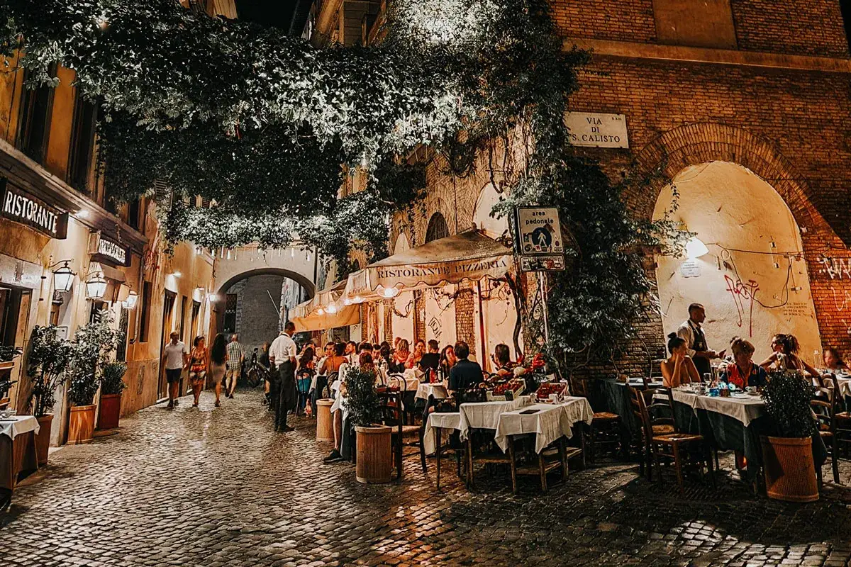 Serata magica a Trastevere, con tavoli all'aperto per scoprire dove mangiare. Vicoli acciottolati, luci soffuse e l'atmosfera romana.