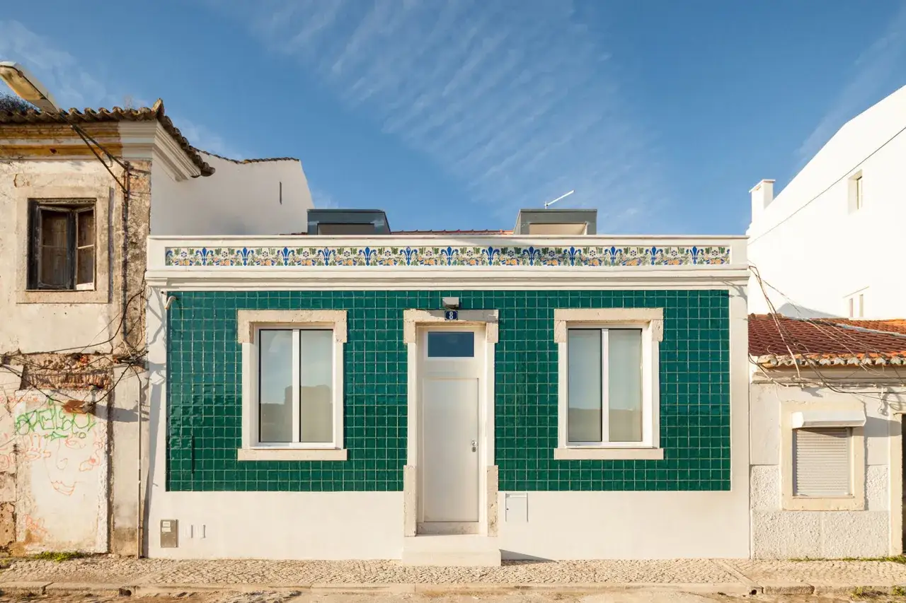 Fachada de casa antigua con azulejos verdes y detalles decorativos, un ejemplo de cómo modernizar una vivienda con estilo.