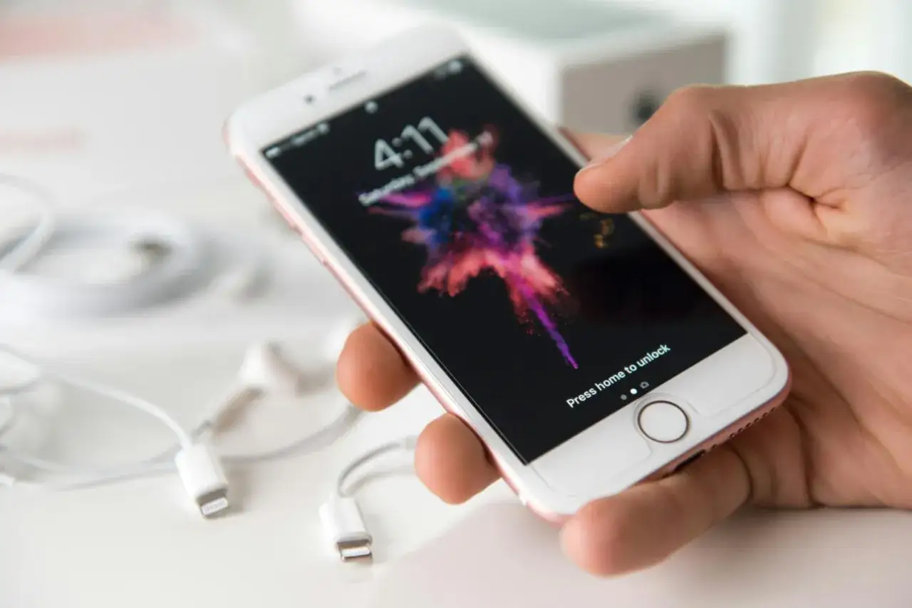 En hand håller en iPhone med en färgstark bakgrundsbild. Kanske är det dags att byta från Android till iPhone?