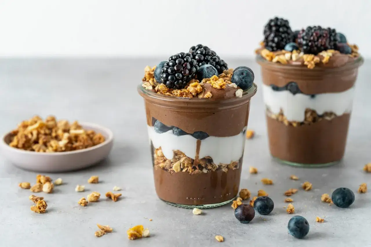 Delizioso chia pudding al cioccolato a strati con yogurt, granola e frutti di bosco freschi.
