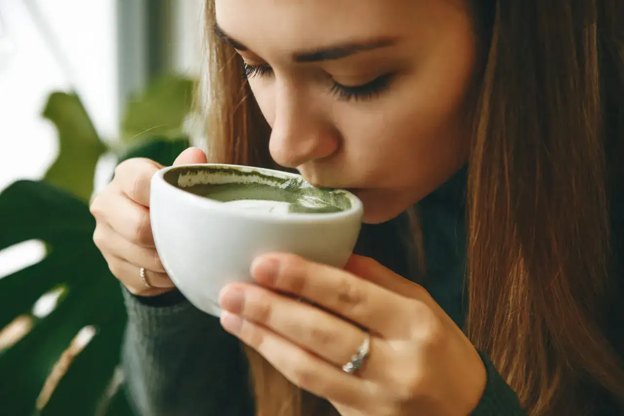dziecko pije matcha latte, uśmiechnięte dziecko z zielonym napojem