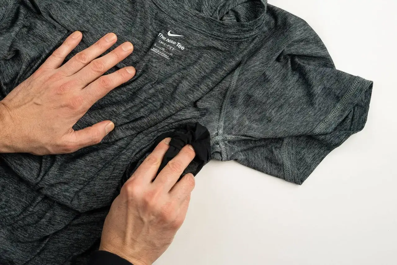 H&auml;nde reinigen ein graues Nike-Shirt, um verkrustete Deoflecken zu entfernen.