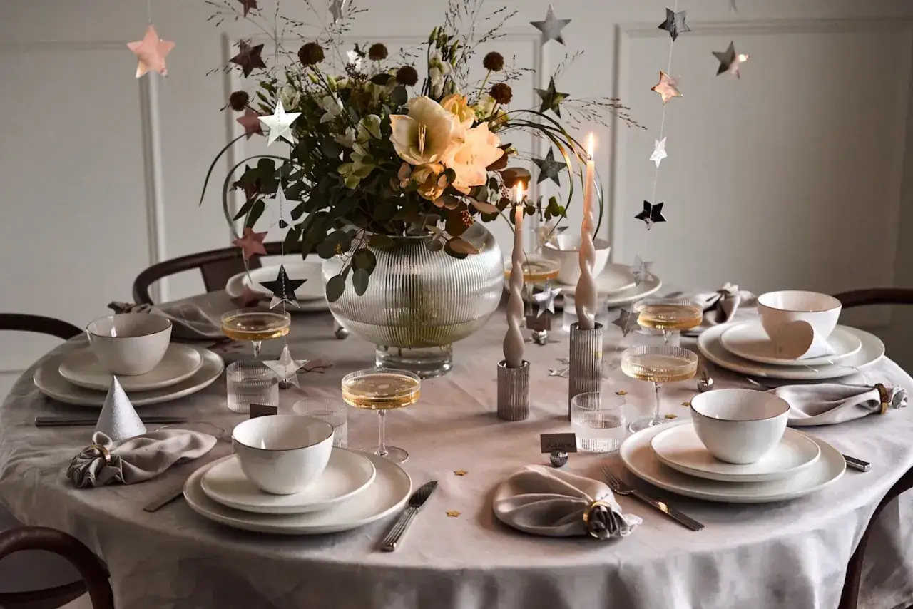 Enkel nyårsdukning med stjärnformade dekorationer, blommor och tända ljus.