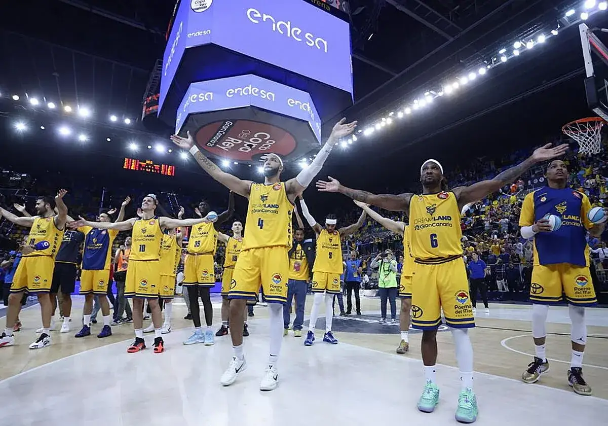 Jugadores del club baloncesto Gran Canaria celebran en la cancha con los brazos en alto.