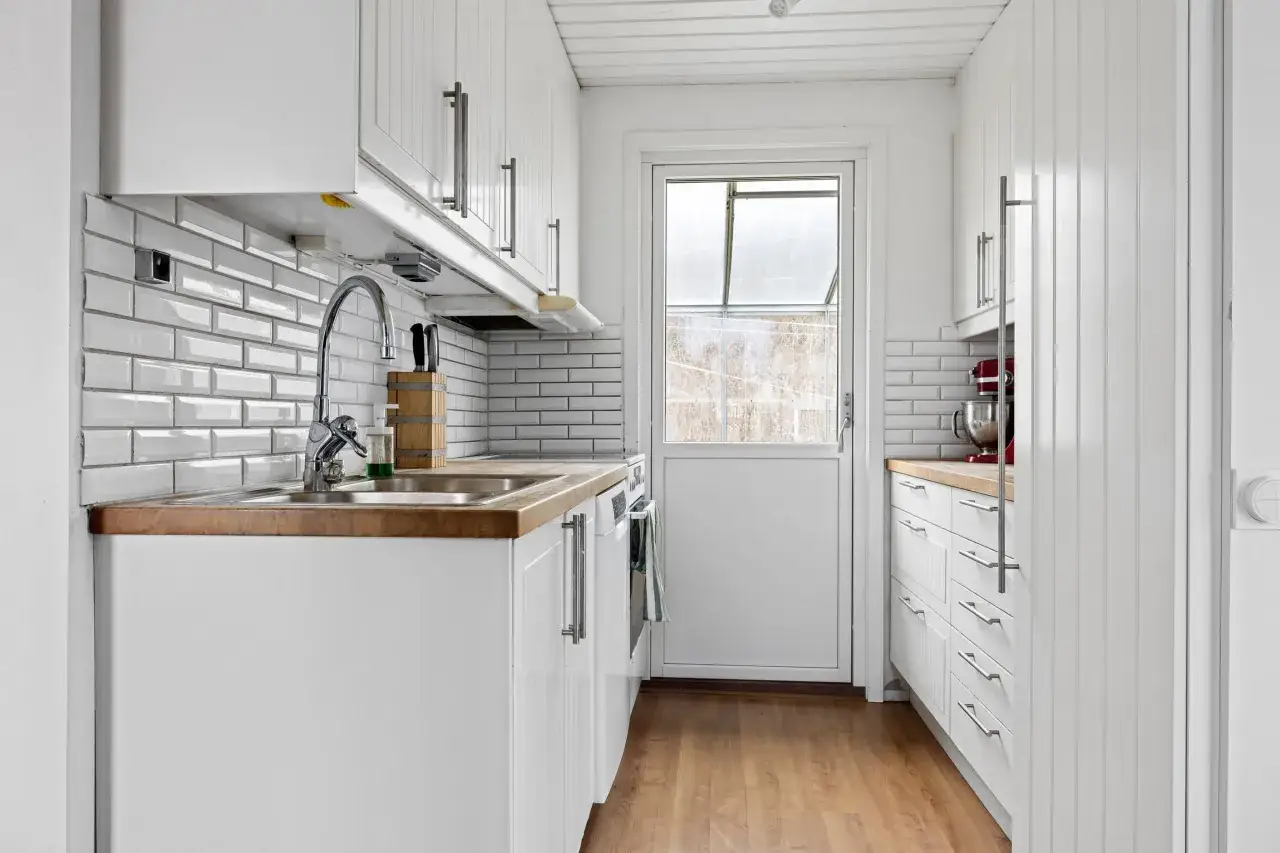Vitt kök med träbänkskiva och vitkaklade väggar. Ett modernt kök som passar perfekt för ett bålsta apartment hotel.