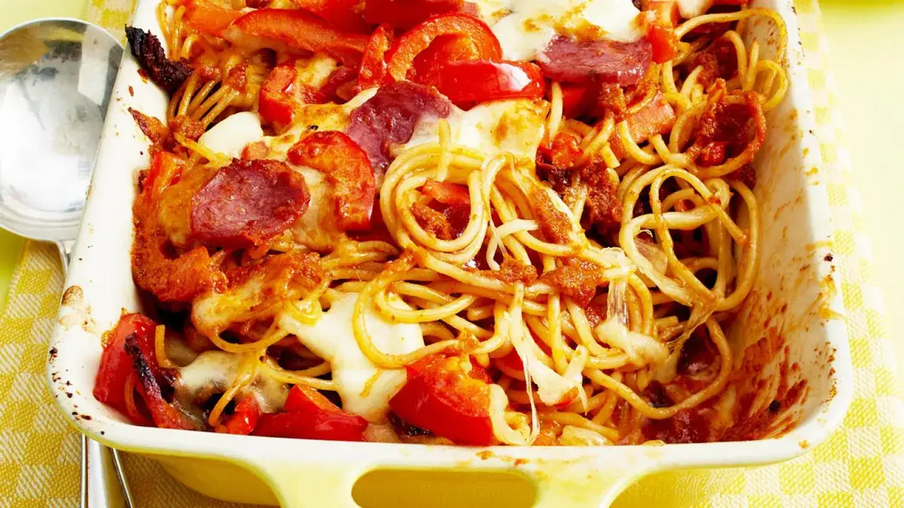 Überbackene Spaghetti mit Paprika, Salami und geschmolzenem Käse, verfeinert mit einem Hauch Paprika Pesto.