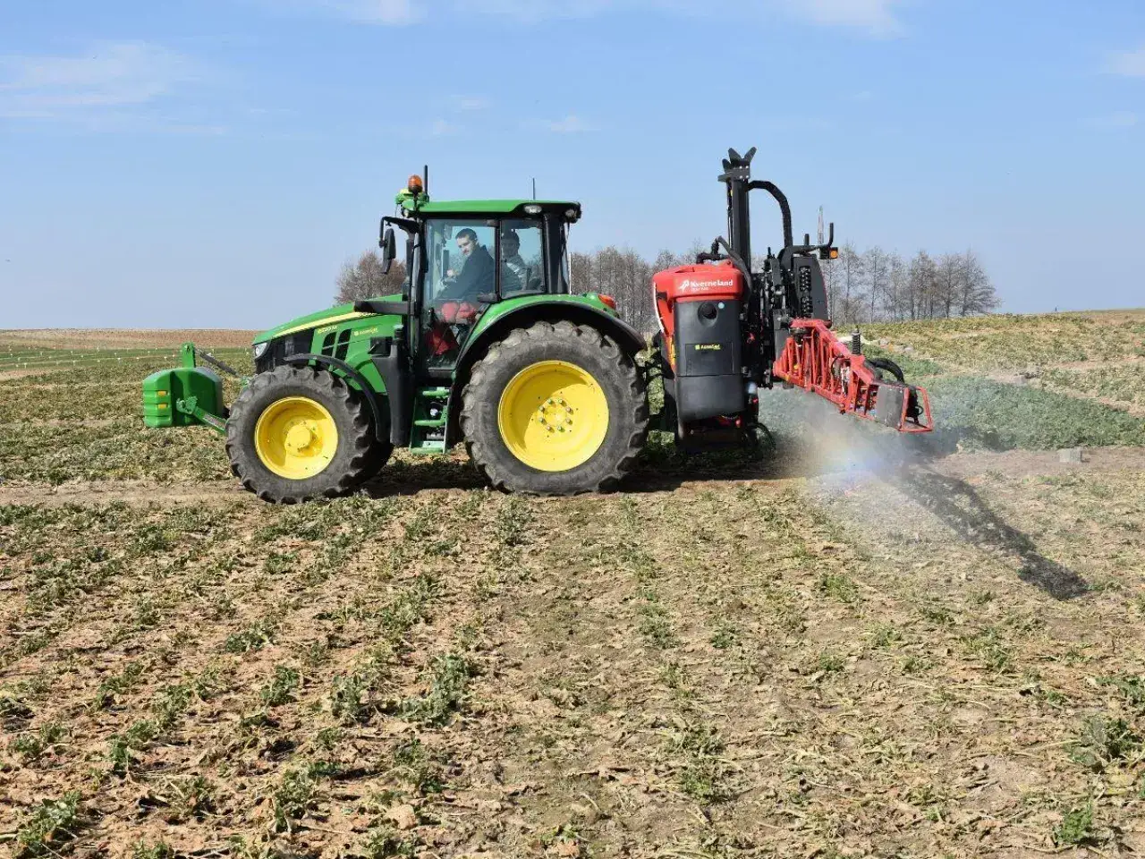 Zielony traktor z opryskiwaczem aplikuje mocznik z inhibitorem na pole.