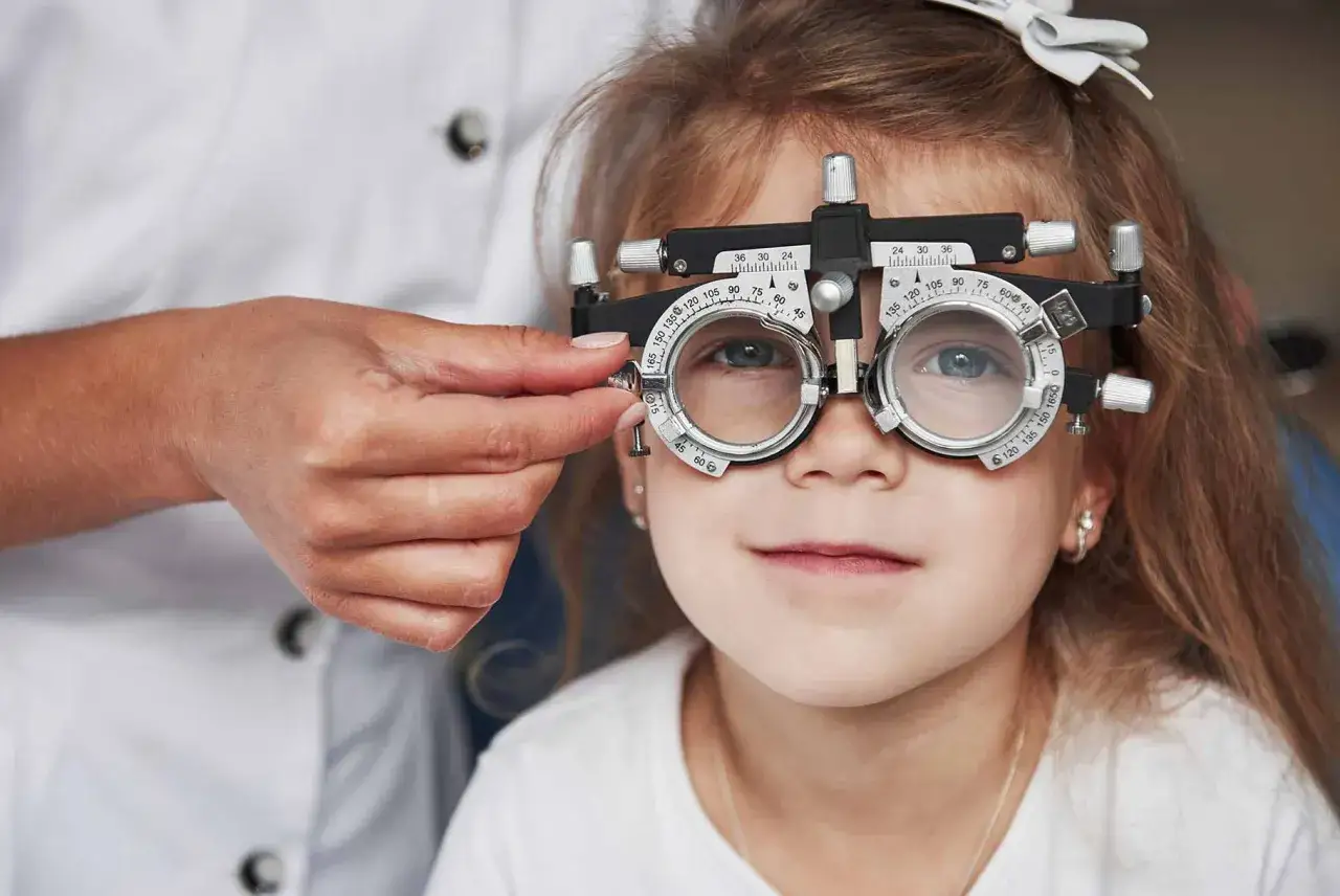 Bambina con occhiali da prova per esame visivo, per valutare i sintomi di ambliopia.