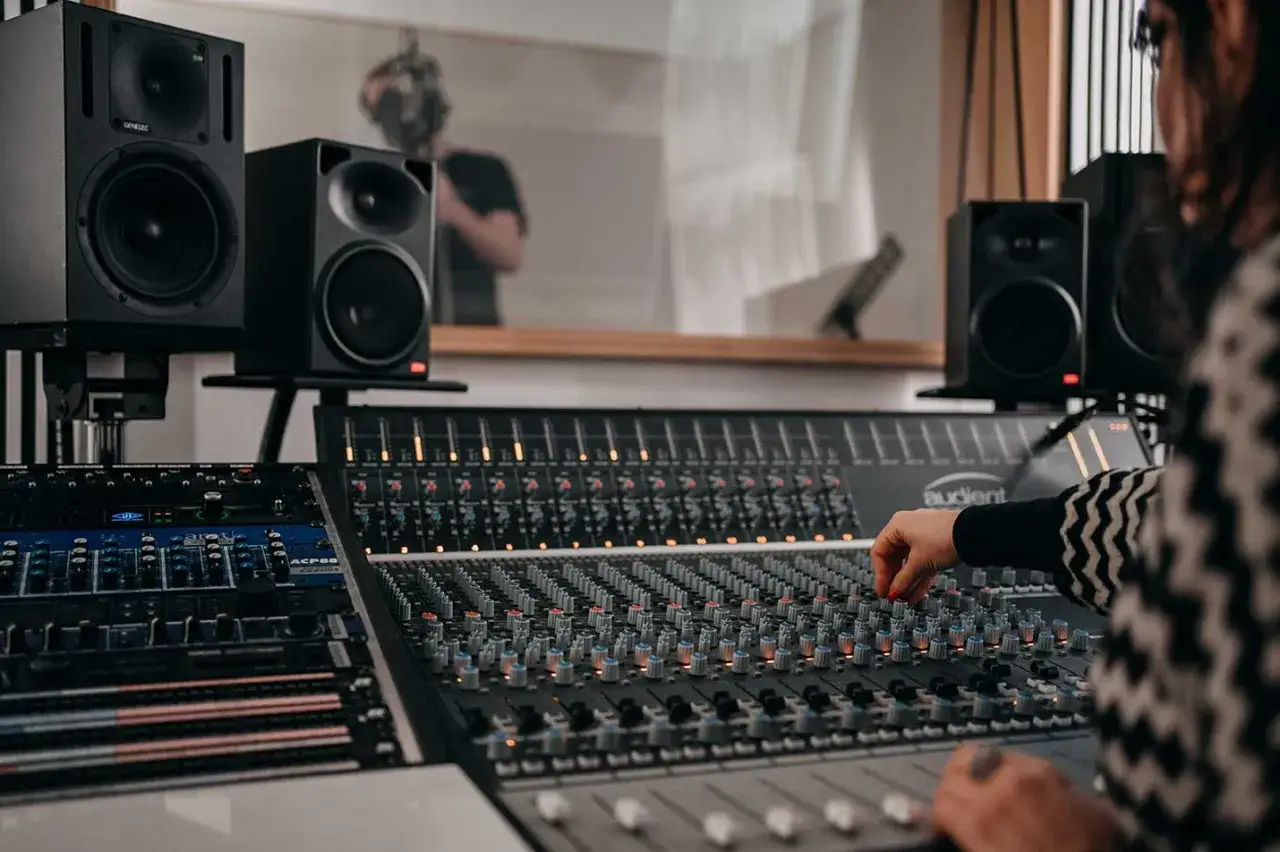 Eine Person am Mischpult, umgeben von Lautsprechern. Perfekt für das Musikproduktion Studium.