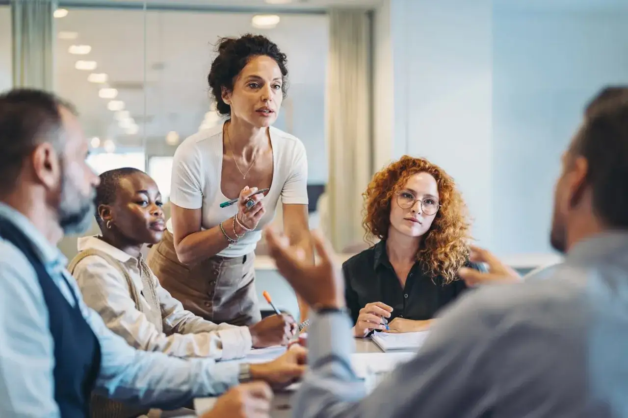 A diverse team discusses ideas, demonstrating effective conflict management by listening and engaging in a productive meeting.