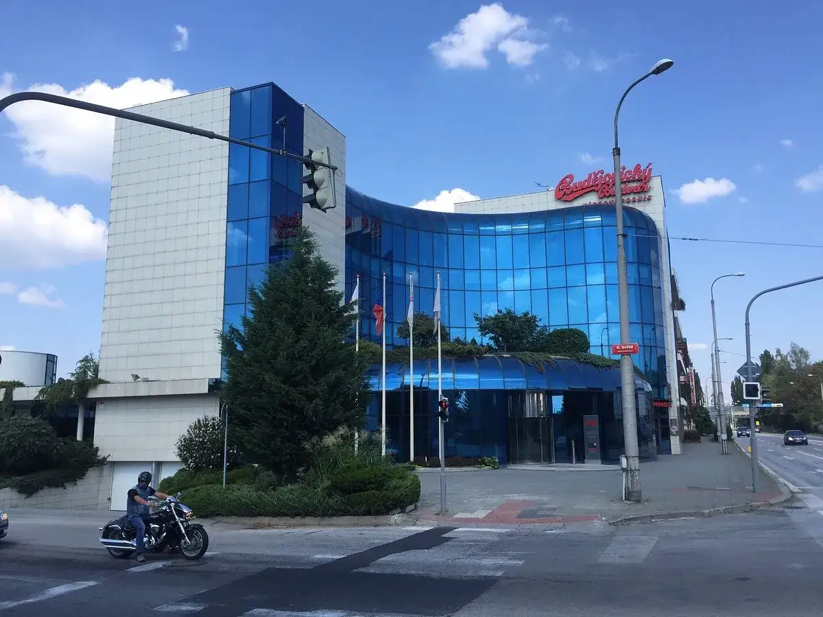 Edificio moderno con logo Budweiser ceca. Un motociclista passa davanti.