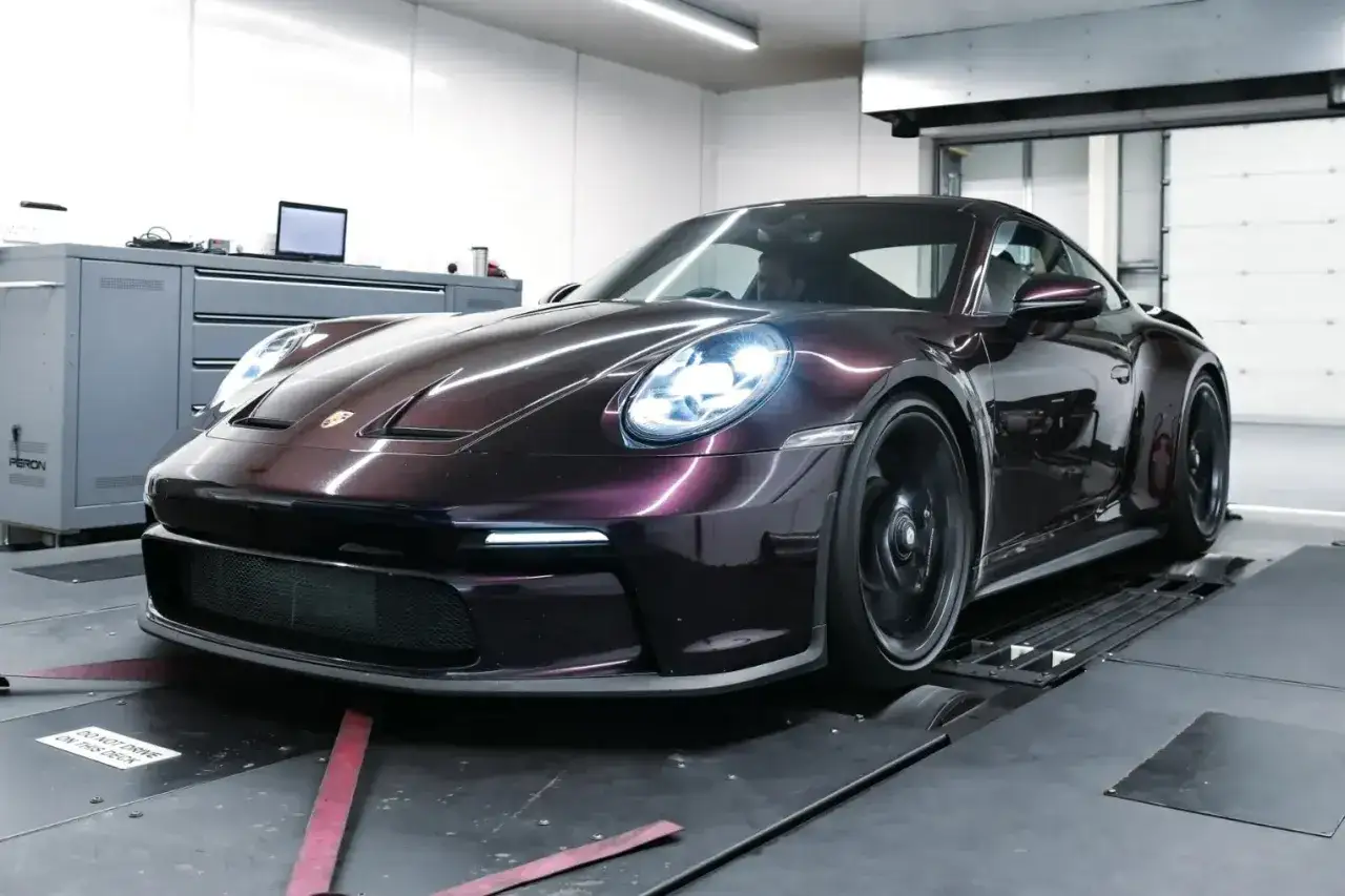 Mroczny, błyszczący Porsche 911 GT3 na hamowni, gotowy do testów mocy.