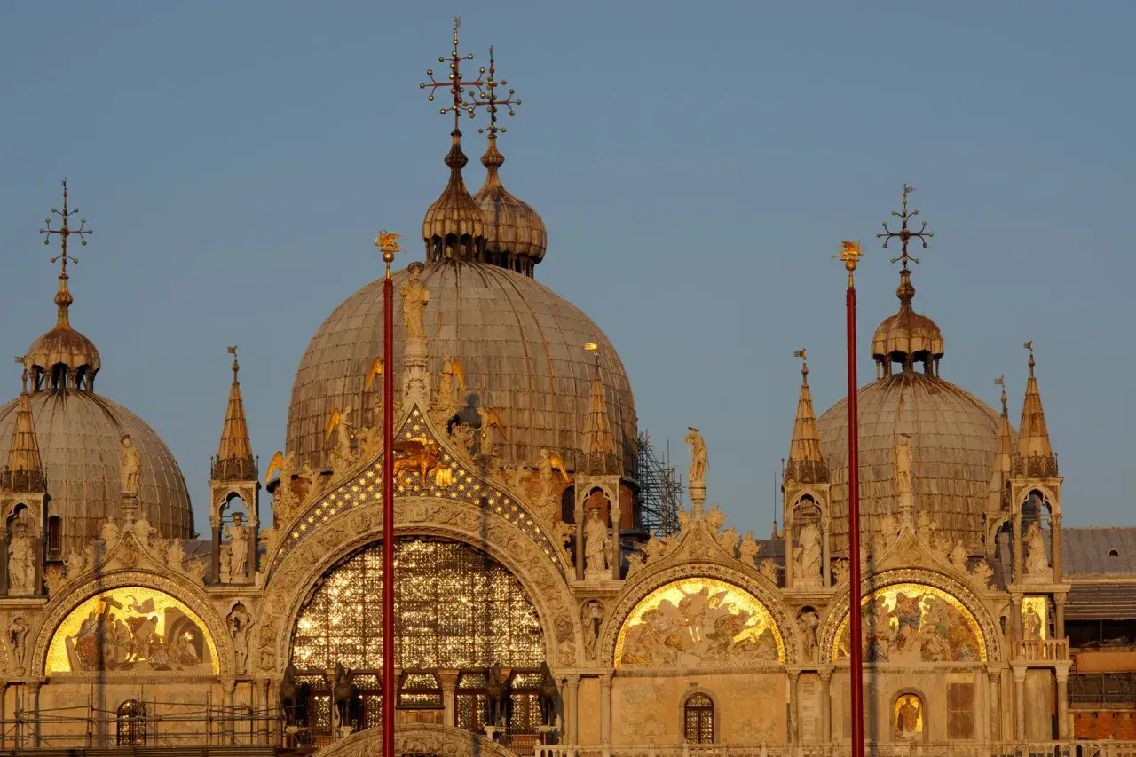 Le maestose cupole di San Marco brillano sotto il sole, ricche di mosaici dorati e sculture antiche.