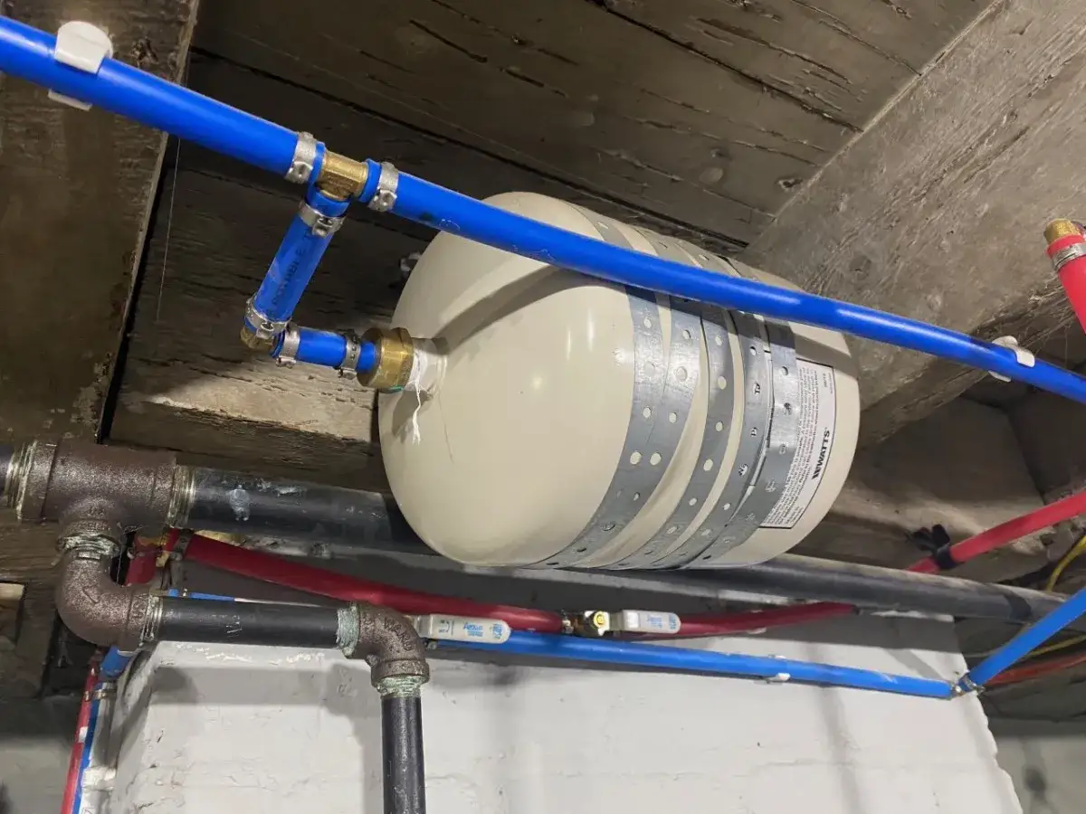 System hydrauliczny z niebieskimi rurkami PEX, zbiornikiem przeponowym i czarnymi rurami.