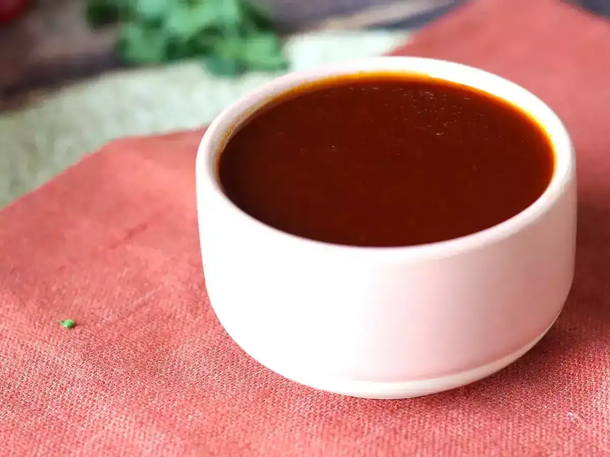 En sk&aring;l med m&ouml;rk, glansig bbq s&aring;s st&aring;r p&aring; en r&ouml;d duk. Perfekt f&ouml;r grillkv&auml;llen!