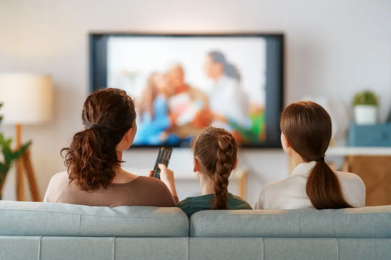 Rodzina ogląda bajkę w telewizji. Uważajmy na szkodliwe bajki dla dzieci, które mogą wpływać na ich rozwój.
