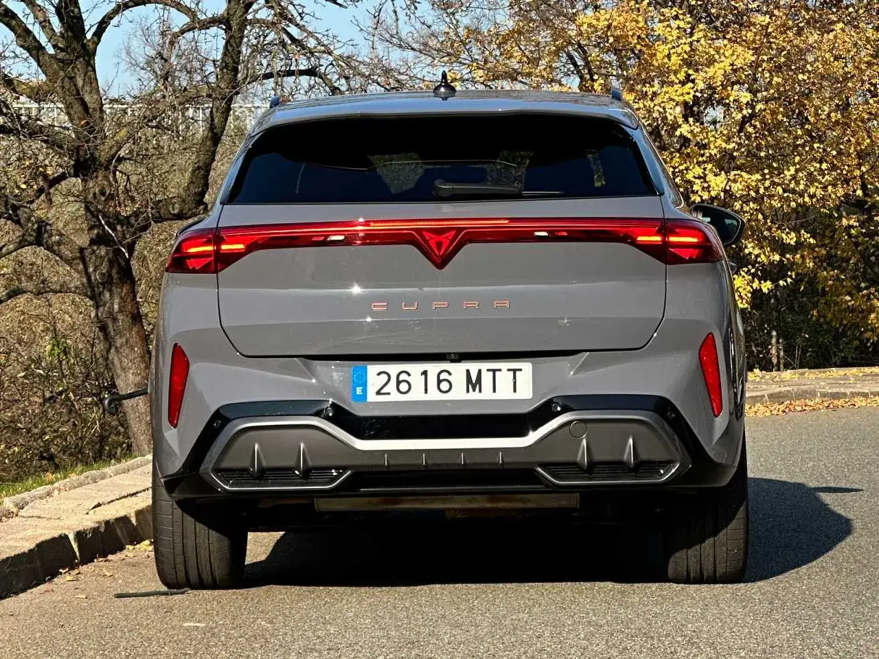 Szary Cupra Terramar z charakterystycznym pasem świateł LED. Zbliżenie na tył auta, gdzie widoczne są detale stylistyczne i tablica rejestracyjna.