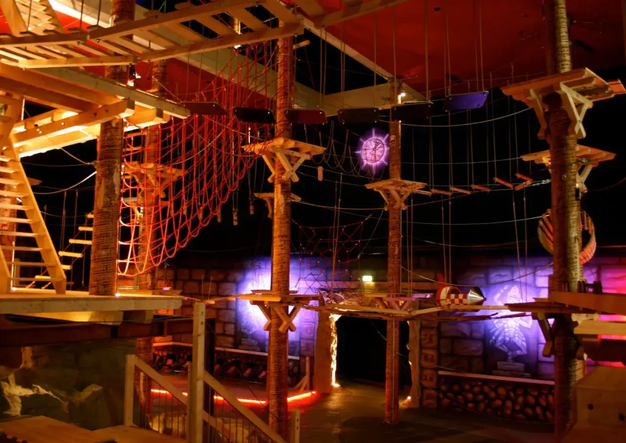 Abenteuerliche Kletterhalle f&uuml;r Kinder mit Netzen, Br&uuml;cken und Plattformen in stimmungsvollem Licht.