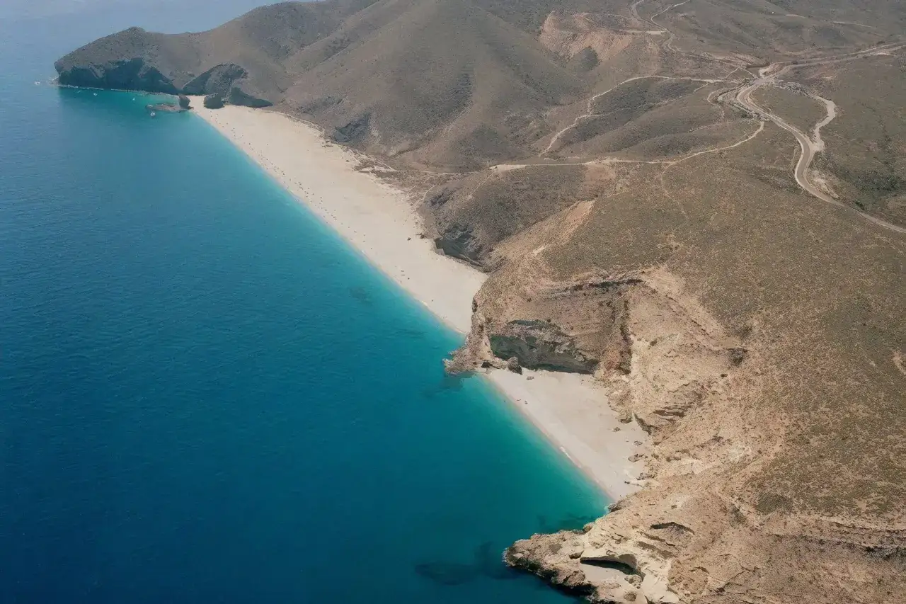 La playa de los Muertos en Carboneras, Almería, es un paraíso de arena blanca y aguas turquesas, rodeada de montañas áridas.