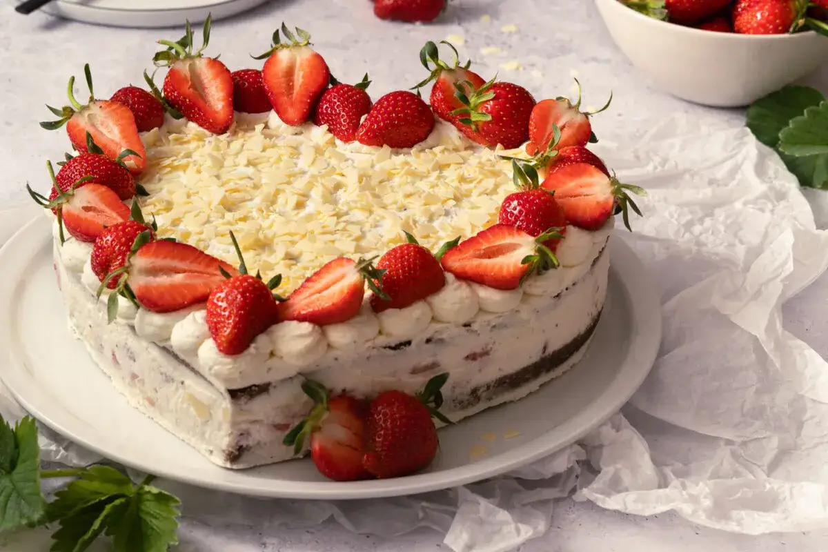 Herzförmiger Kuchen zum Muttertag, dekoriert mit frischen Erdbeeren und weißer Schokolade.