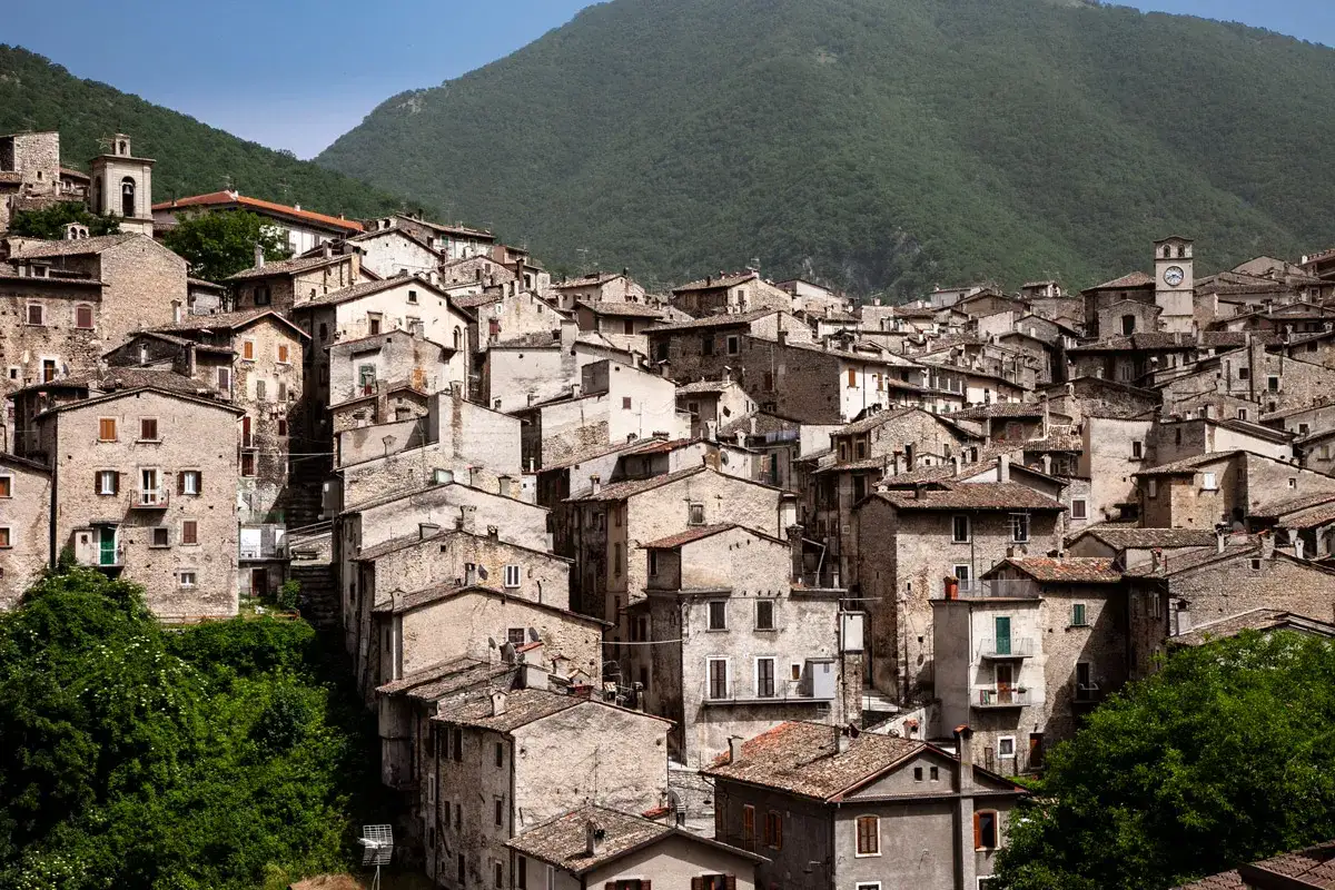 Borgo antico aggrappato al monte, con case in pietra e tetti rossi. Un campanile e un orologio segnano il tempo. Un luogo da scoprire vicino al lago di Scanno.