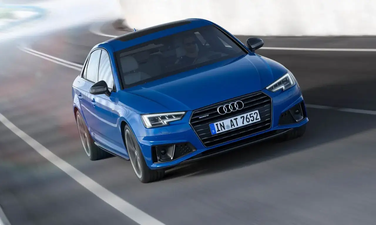 Blå Audi A4 B9 kör på en kurvig väg med suddiga vita linjer.