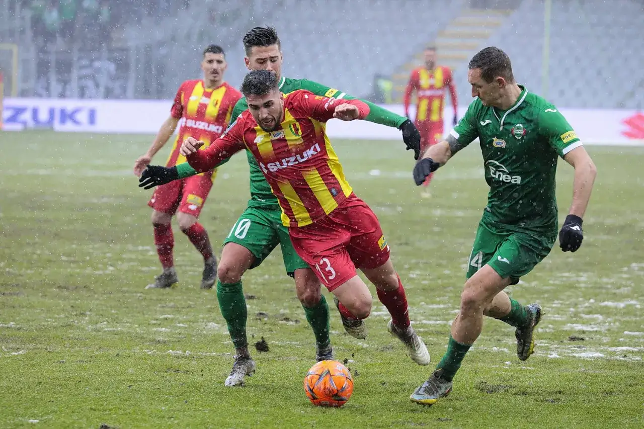 Piłkarze Radomiaka Radom walczą o piłkę z Koroną Kielce w deszczu.