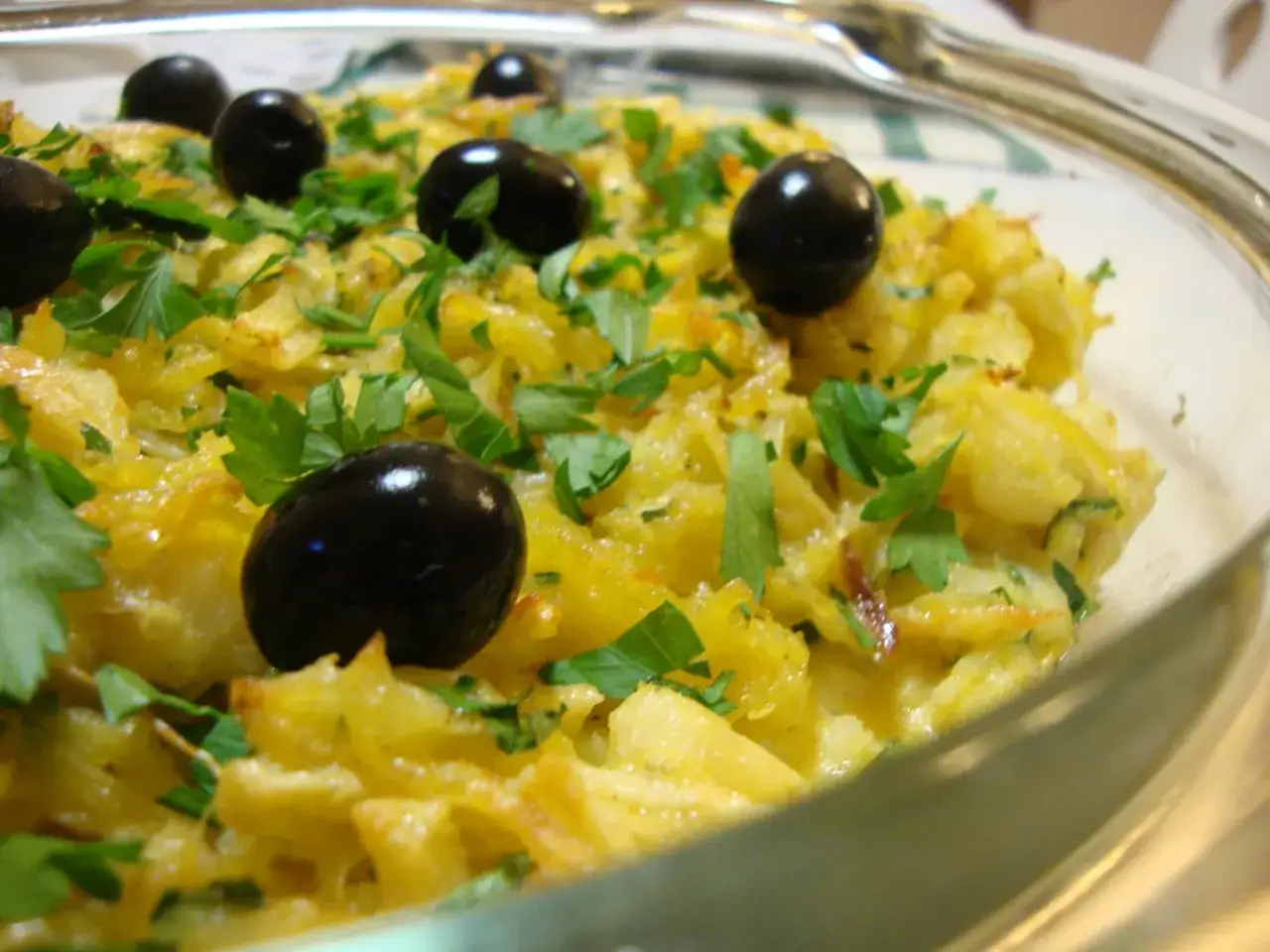 Un plat de bacalhau à brás, garni d'olives noires et de persil frais, prêt à être dégusté.