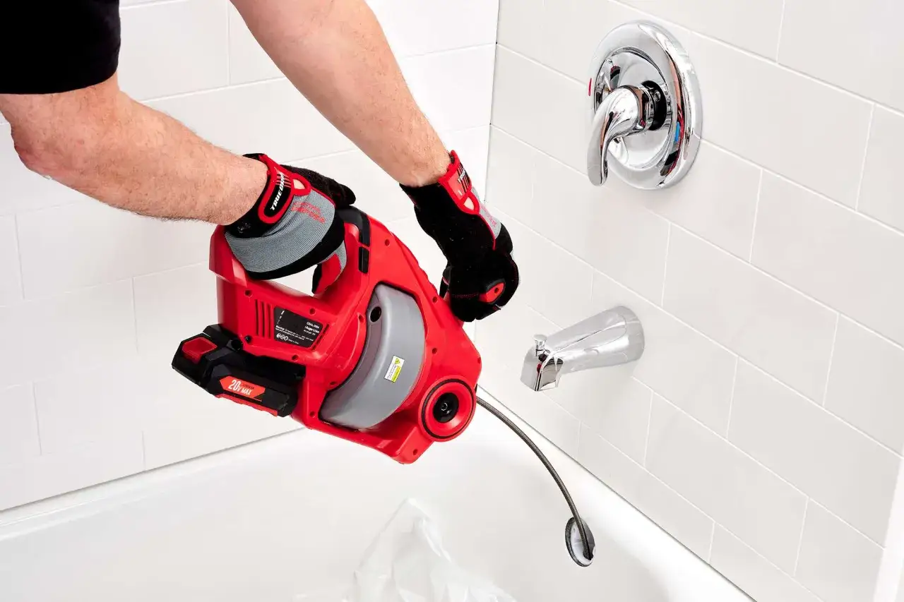 Utilisation d'un d&eacute;boucheur &eacute;lectrique pour comment d&eacute;boucher une baignoire rapidement. L'outil est ins&eacute;r&eacute; dans le drain de la baignoire.