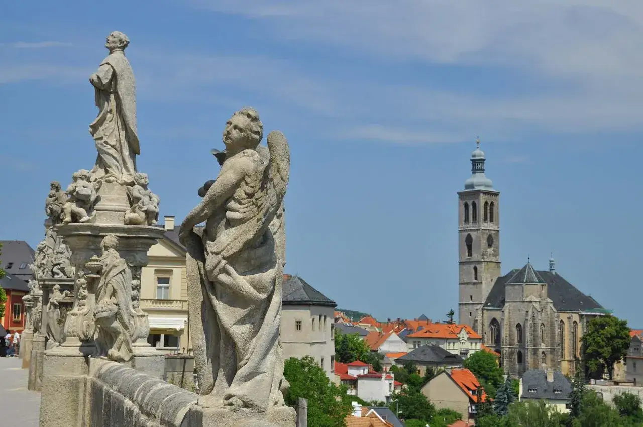 Kamienne rzeźby aniołów na moście w Kutnej Horze, z widokiem na zabytkowe miasto i kościół. Atrakcje turystyczne Czech.