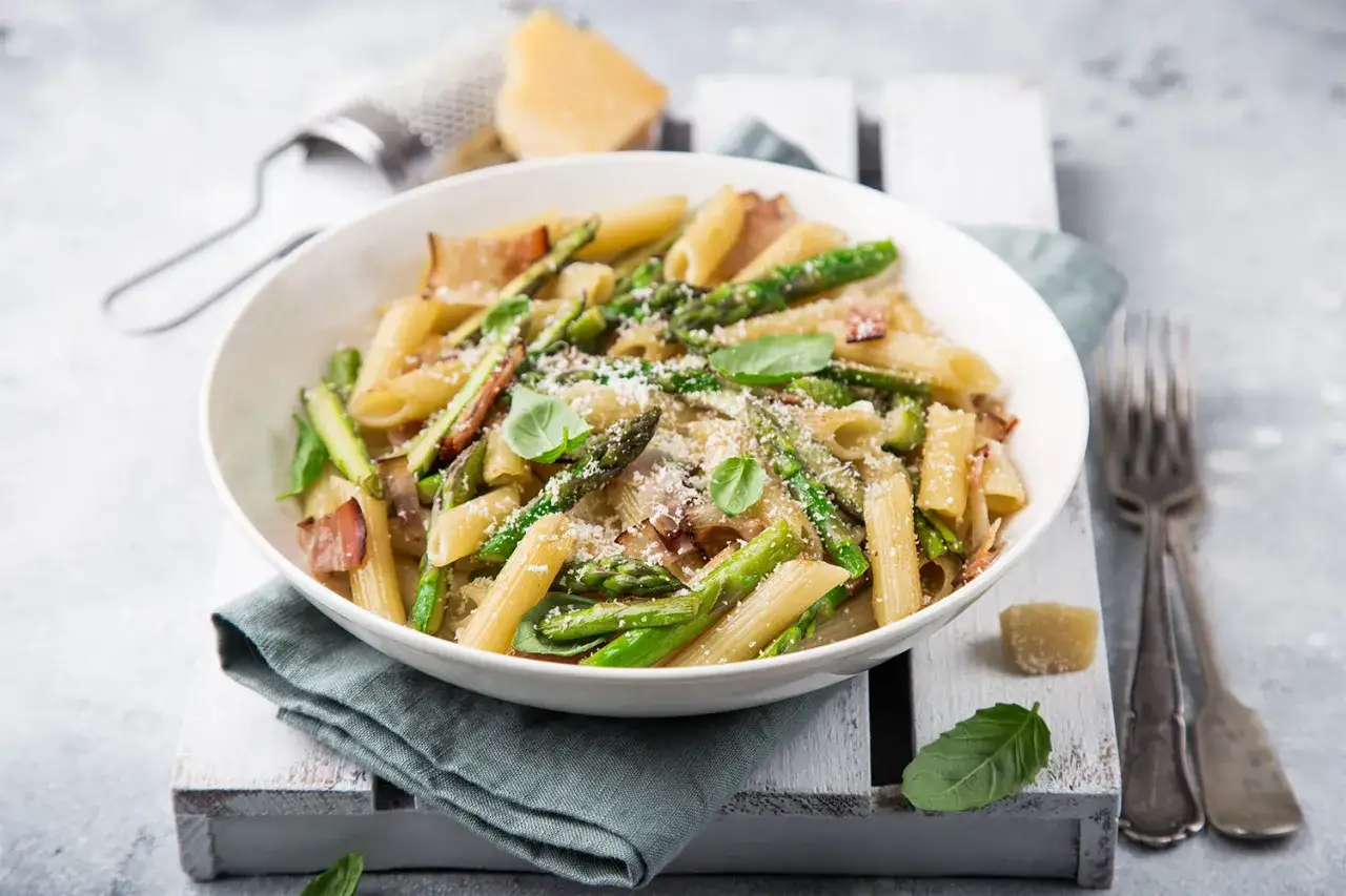 Penne z szparagami i boczkiem, posypane parmezanem. Pyszny makaron bez glutenu, idealny na lekki obiad.
