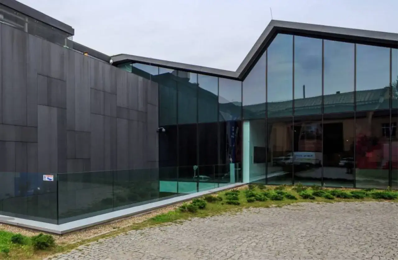 Nowoczesna architektura Muzeum Sztuki Współczesnej Mocak w Krakowie. Szklane fasady odbijają niebo i otoczenie.