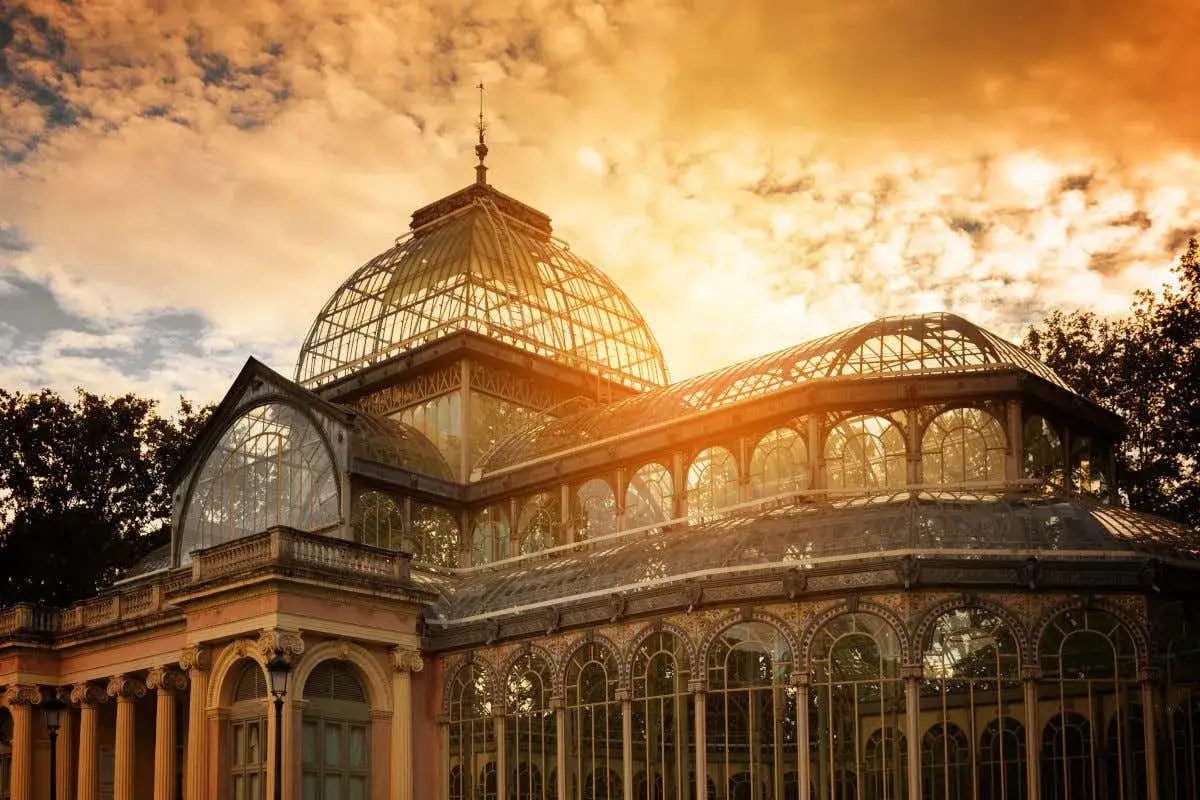 Palacio de Cristal en el Retiro, un lugar imprescindible que ver en Madrid, bañado por la luz dorada del atardecer.
