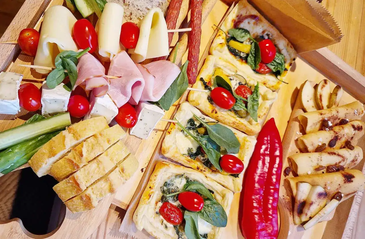 Pyszne przekąski na grilla: tartaletki ze szpinakiem, ser, wędliny, pieczywo, pomidorki i papryka.
