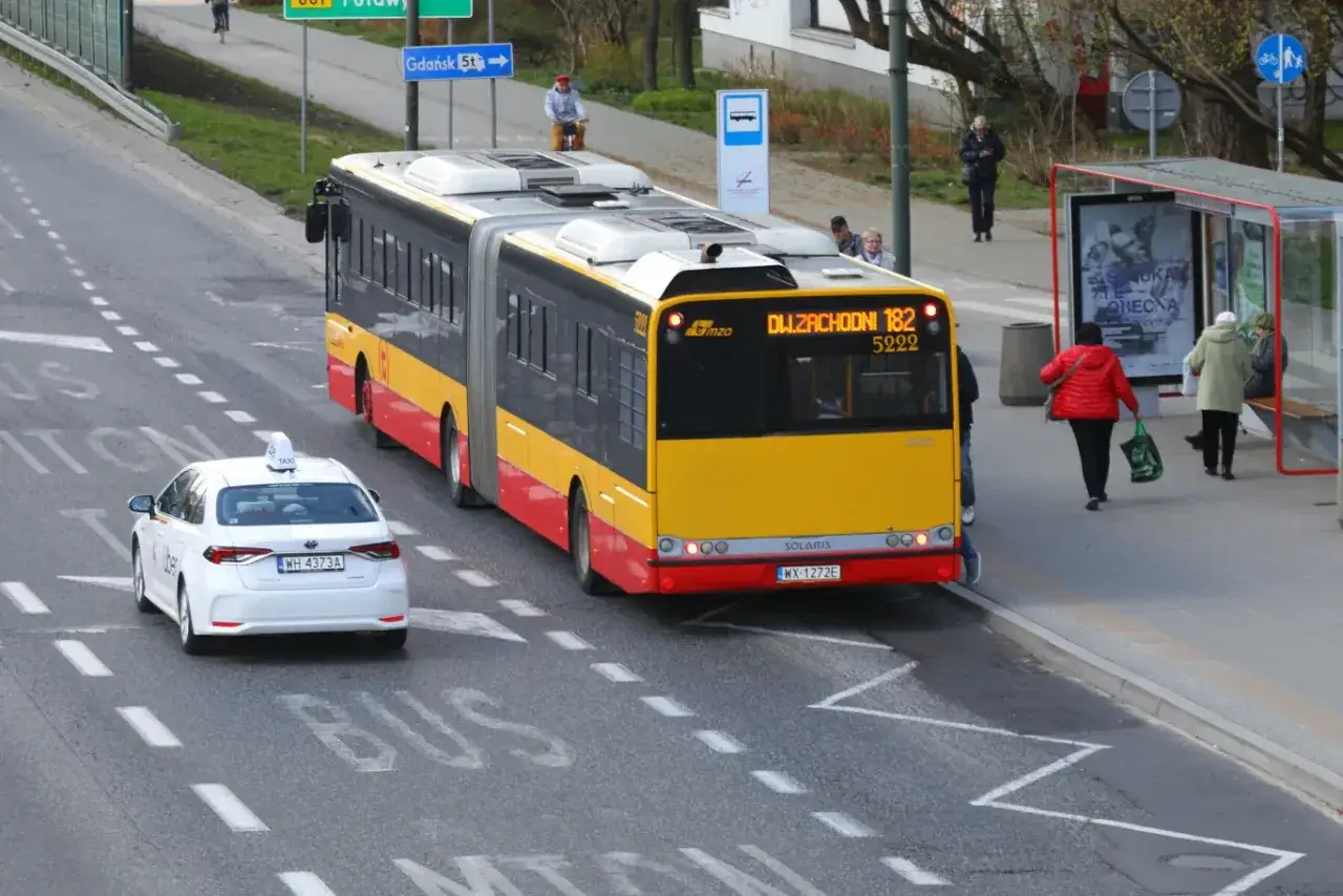 Autobus linii 182 zbliża się do przystanku, a biała taksówka Uber czeka, sugerując, że autobus ma pierwszeństwo.