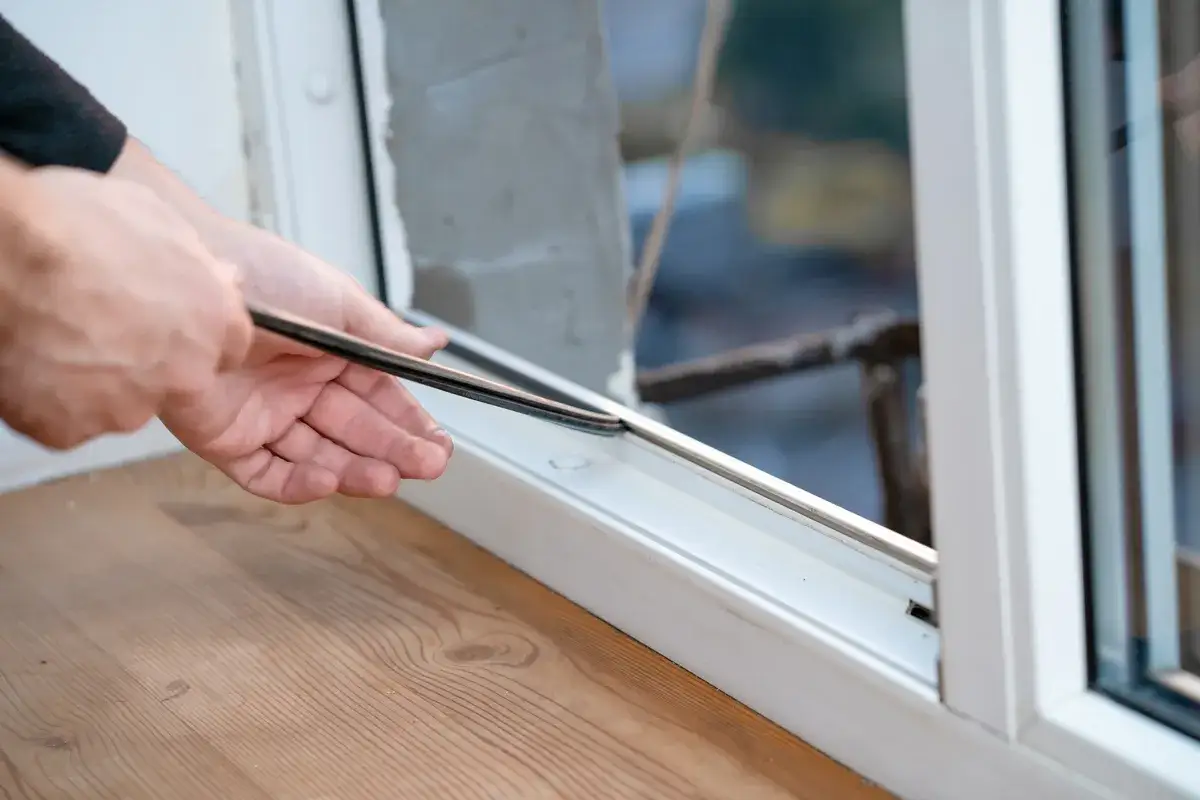 H&auml;nde f&uuml;hren eine Dichtung ein, um ein Fenster abzudichten.