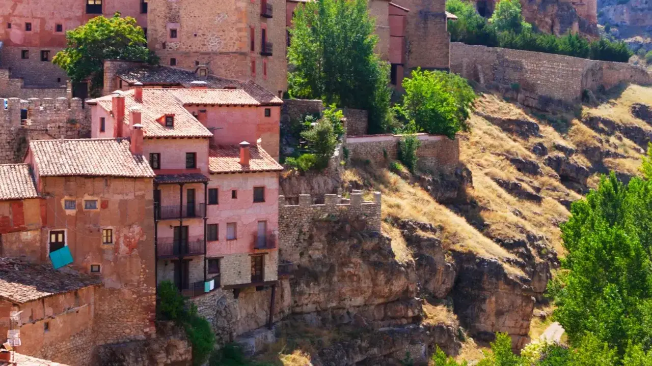 Casas de piedra y encaladas se aferran a un acantilado, creando un paisaje de 5 villas con tejados rojos y balcones.