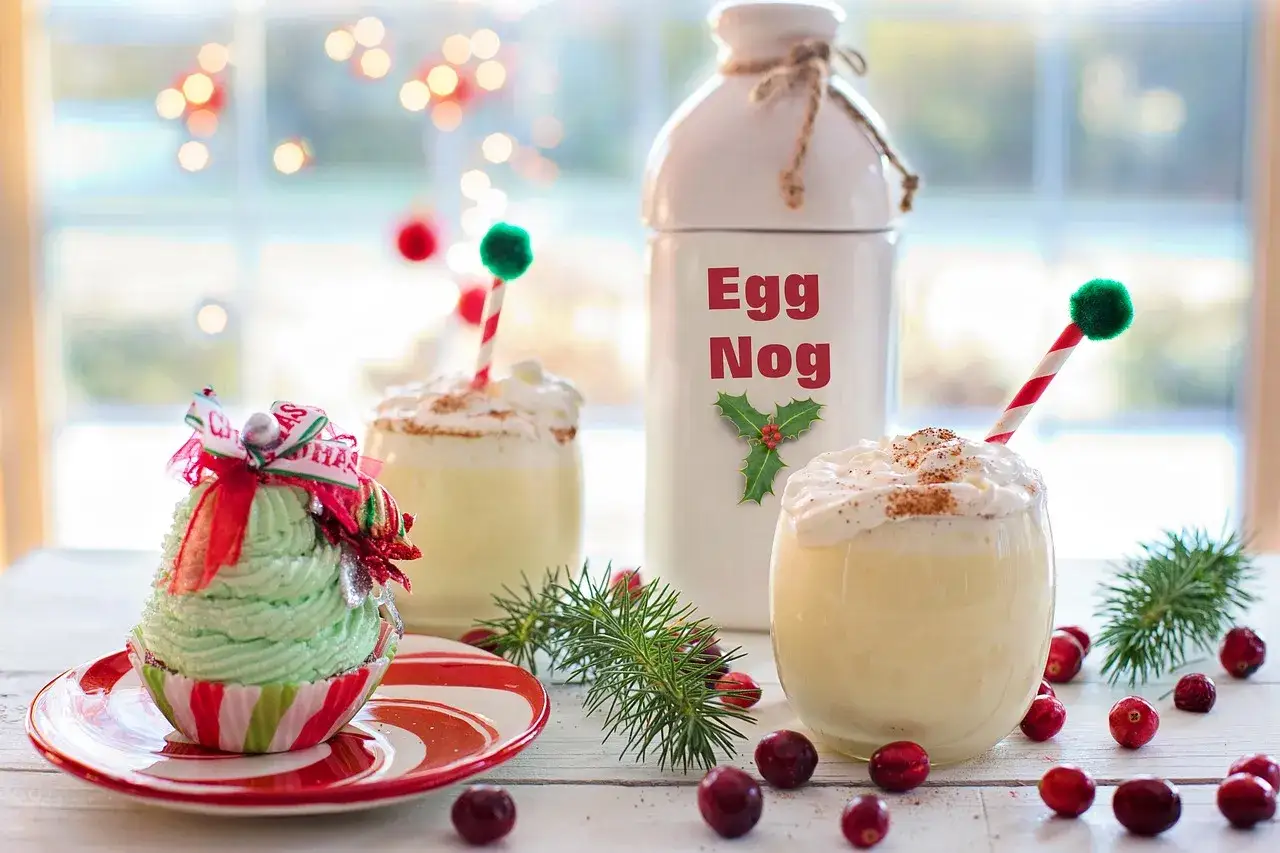 Un bicchiere di eggnog cremoso, decorato con panna montata e cannella, pronto per essere gustato. La ricetta perfetta per le feste!