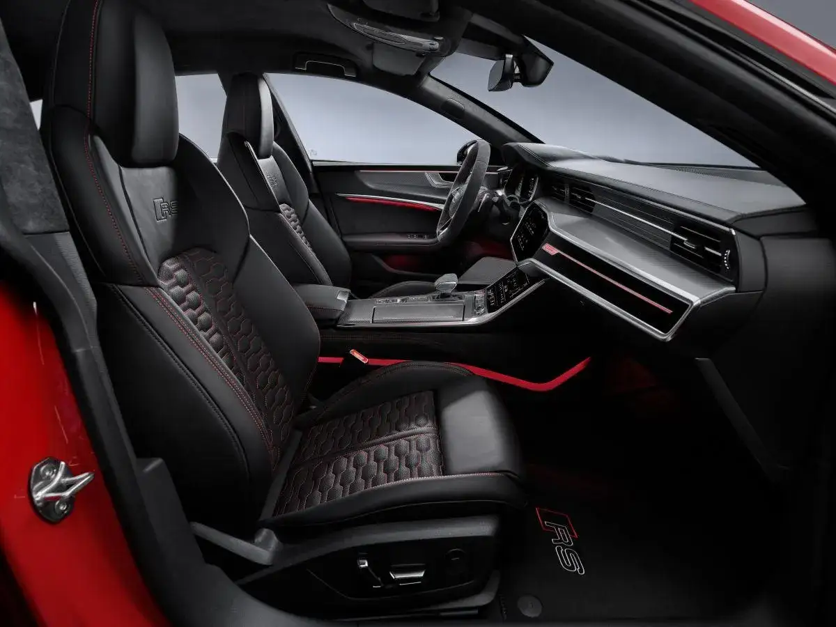 Wnętrze Audi RS 7: czarne skórzane fotele z czerwonymi przeszyciami, sportowa kierownica i nowoczesna deska rozdzielcza.