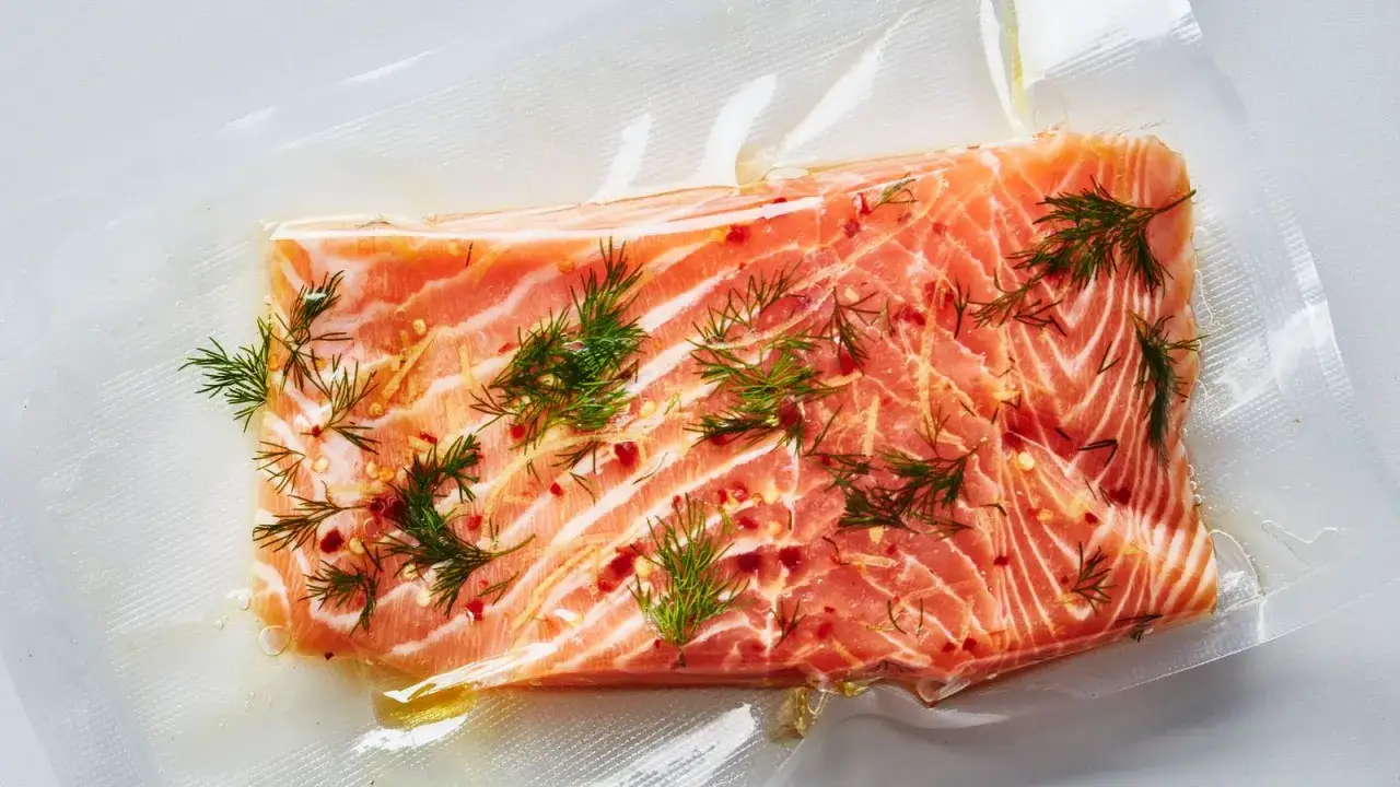 En bit lax för sous vide-tillagning, kryddad med dill och chili, ligger i en vakuumpåse.