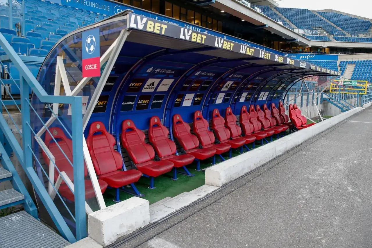 Puste czerwone fotele na ławce rezerwowych stadionu piłkarskiego. Ile zmian można zrobic w piłce nożnej?