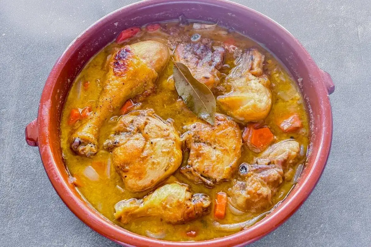 Muslos de pollo en salsa, un plato casero que evoca la receta de la abuela, con zanahorias y laurel en una cazuela de barro.